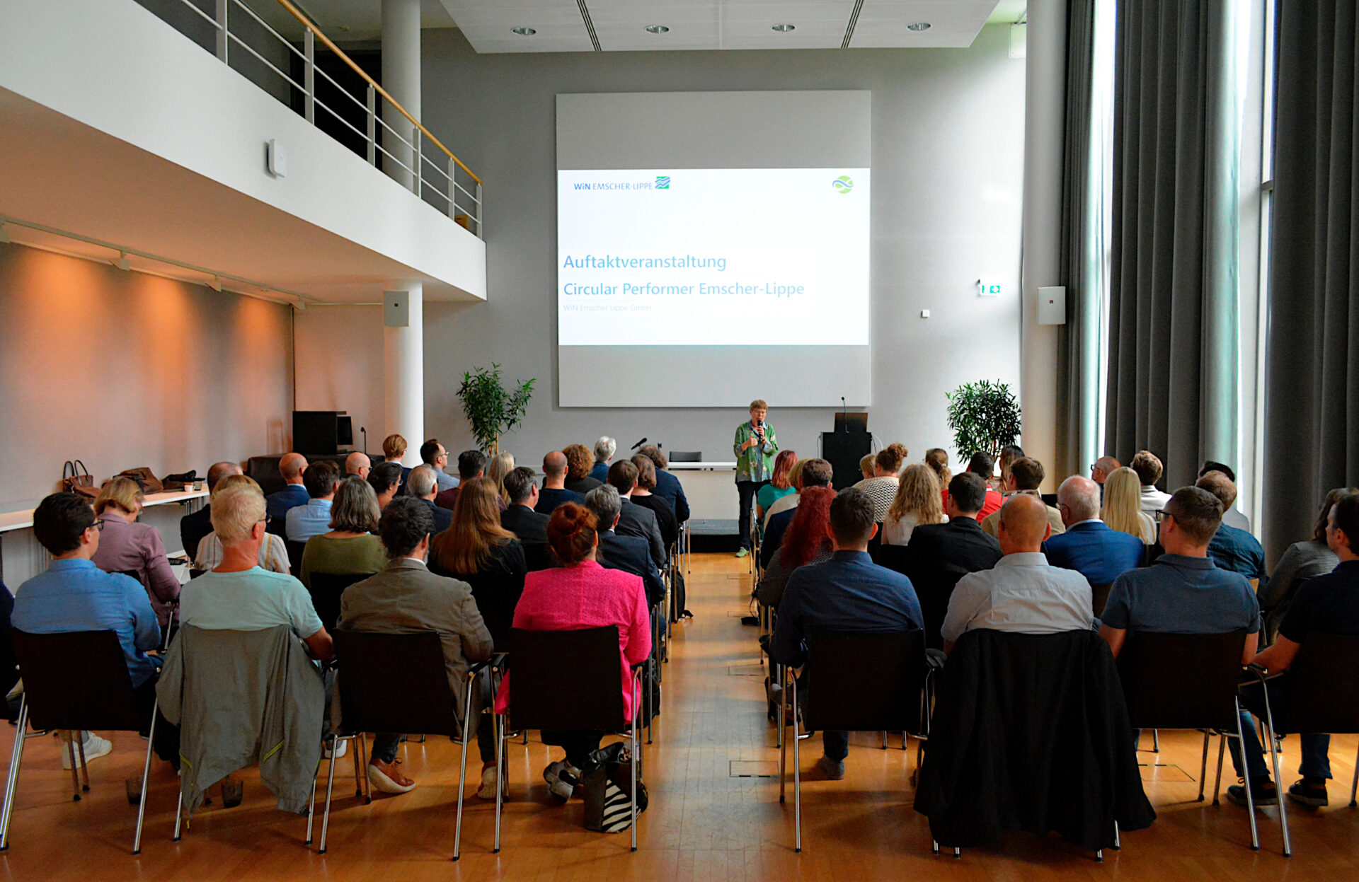 Das Bild zeigt die Referenton Dr. Babette Nieder. Sie steht vor einem Publikum. Im Hintegrund ist: Auftaktveranstaltung Circular Performer Emscher-Lippe auf ihrer Präsentation zu lesen.