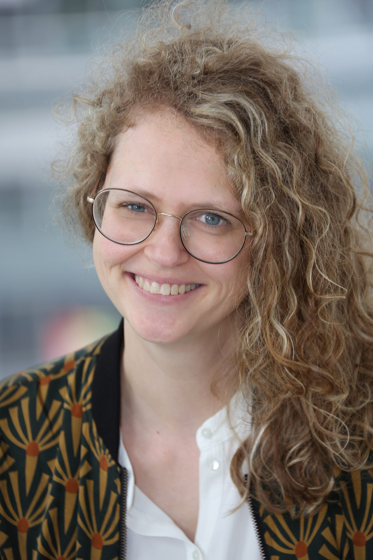 Das Bild zeigt Anna-Katharina Jung eine Frau mit blonden langen Haaren, einer großen Brille und einem großen Lächeln.